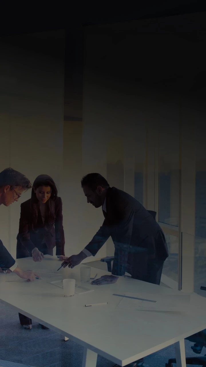 Three people stood around a table having a meeting